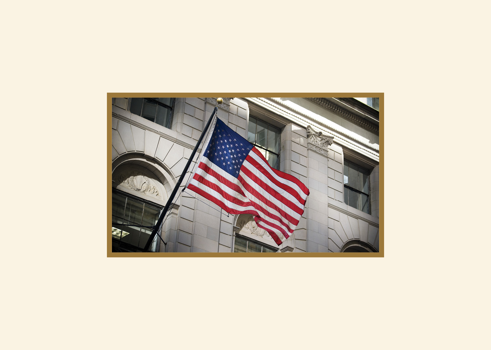 How Financial Advisors Use Client Cards After Market Drops An image of an American flag waving in front of a stone building with a gold frame. The thick border is cream-colored.
